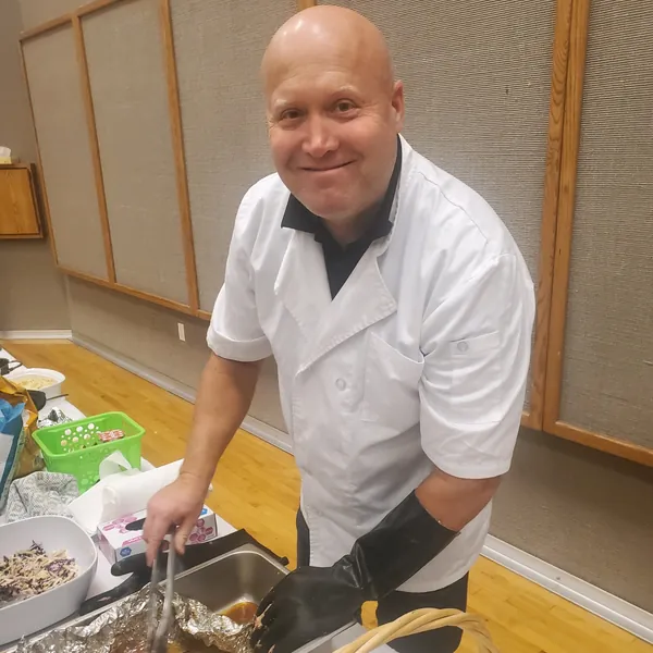 Tom smiling while serving pulled pork at a catering event